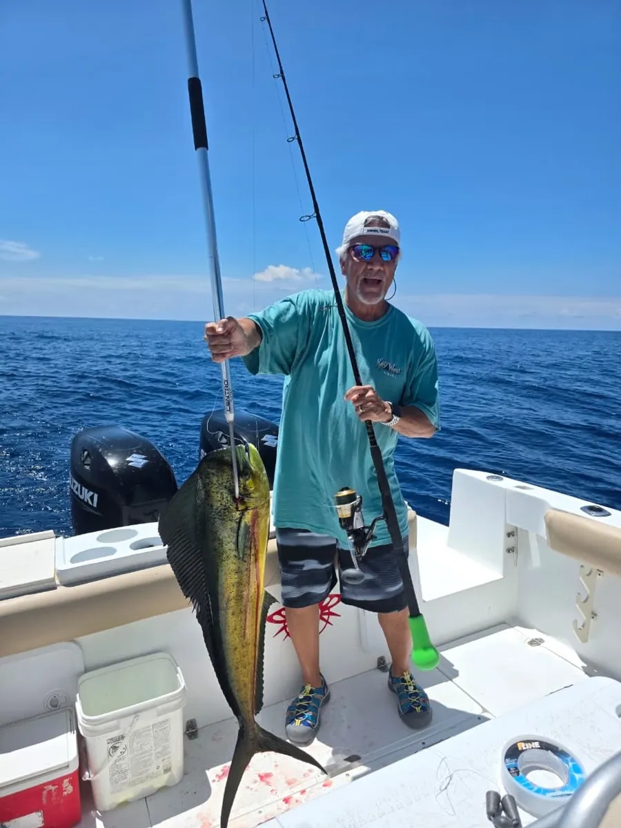 An angler holding a mahi mahi at sunset off Playa Garza