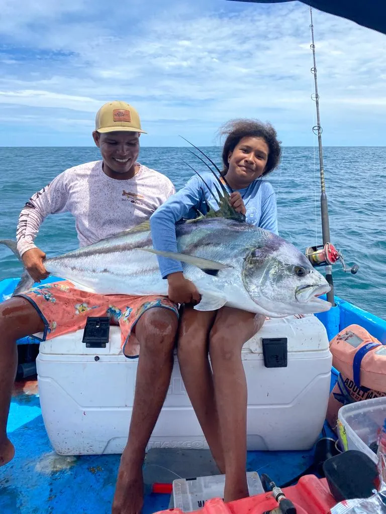 A young guest and a crew member holding a roosterfish on the boat off Playa Garza