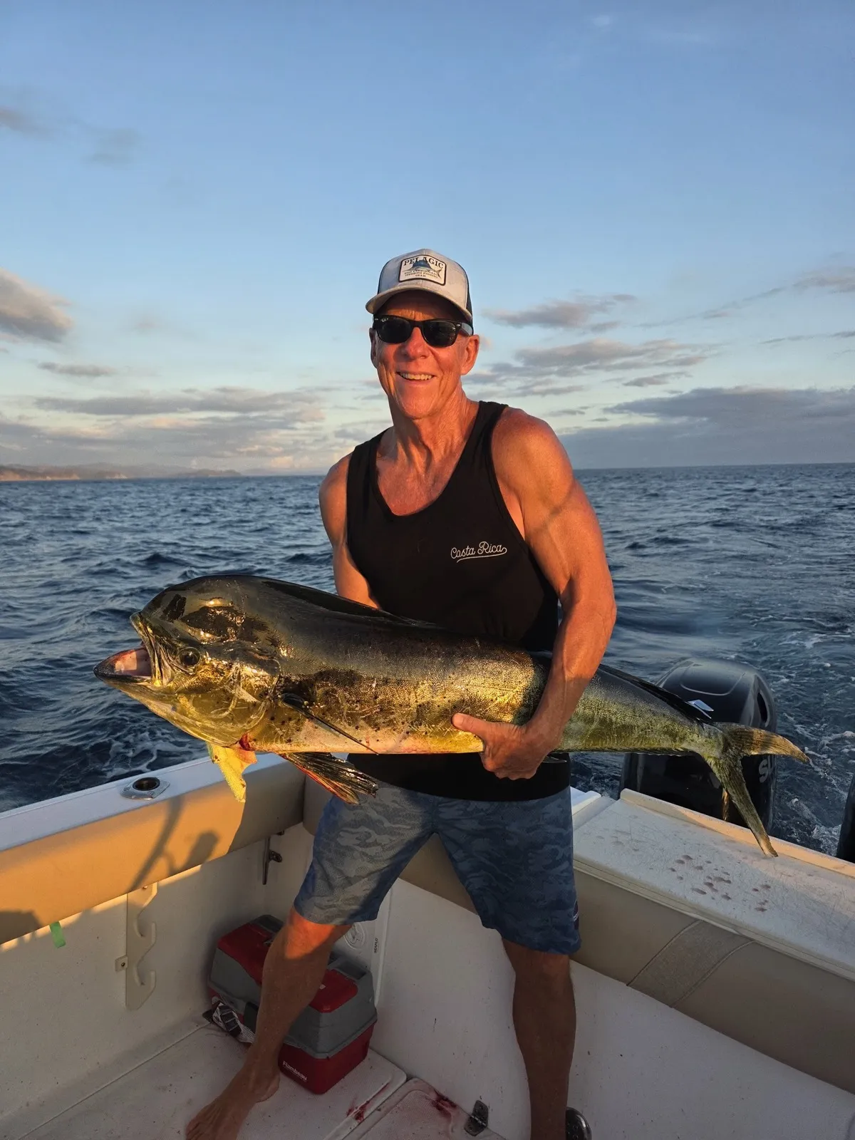 An angler holding a mahi mahi at sunset off Playa Garza