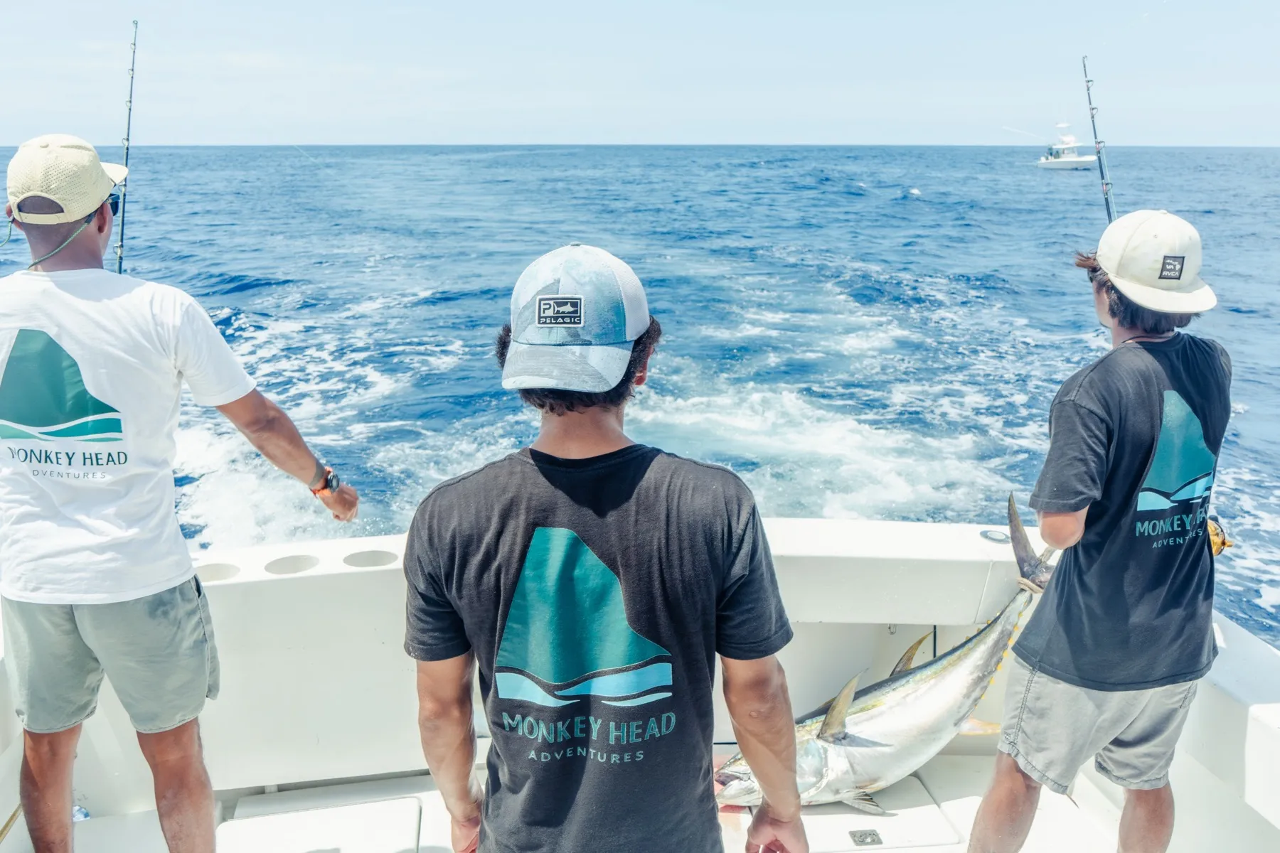 Three Monkey Head crew in branded shirts fishing from the stern off Playa Garza